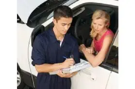 A man and woman are writing on paper in the car.